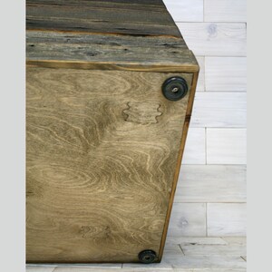 Puede incluir: Una caja de almacenamiento de madera con un acabado de madera natural. La caja tiene una forma rectangular y est&aacute; hecha de madera recuperada. El fondo de la caja est&aacute; hecho de madera contrachapada y tiene cuatro pies de goma negra.