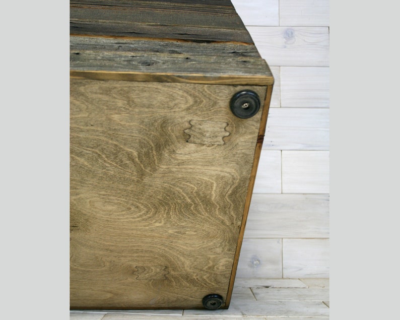 Puede incluir: Una caja de almacenamiento de madera con un acabado de madera natural. La caja tiene una forma rectangular y est&aacute; hecha de madera recuperada. El fondo de la caja est&aacute; hecho de madera contrachapada y tiene cuatro pies de goma negra.