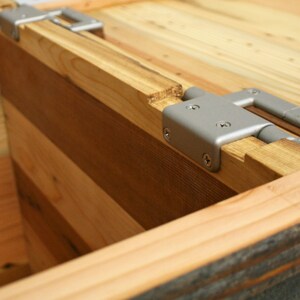 Puede incluir: Primer plano de una caja de madera con una bisagra plateada. La caja est&aacute; hecha de diferentes tipos de madera, lo que le da un aspecto &uacute;nico y r&uacute;stico.