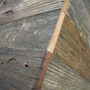 Puede incluir: Primer plano de una caja de madera hecha de tablones de madera recuperada. La madera tiene un aspecto natural y r&uacute;stico con nudos y patrones de veta. La caja est&aacute; hecha de varios tipos de madera diferentes, creando una textura &uacute;nica e interesante.