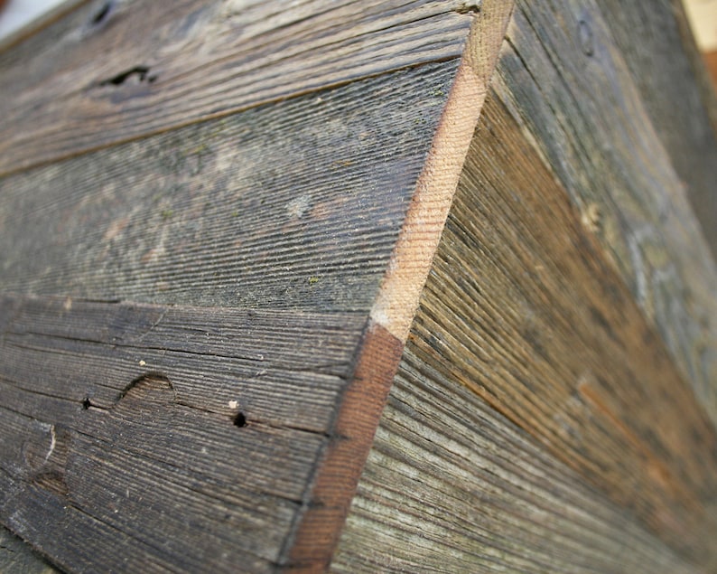 Puede incluir: Primer plano de una caja de madera hecha de tablones de madera recuperada. La madera tiene un aspecto natural y r&uacute;stico con nudos y patrones de veta. La caja est&aacute; hecha de varios tipos de madera diferentes, creando una textura &uacute;nica e interesante.