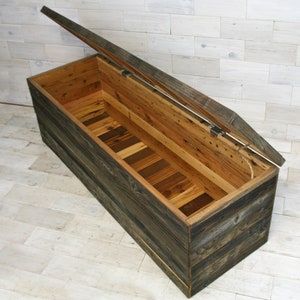 Puede incluir: Un gran cofre de almacenamiento de madera con tapa con bisagras, hecho de madera recuperada con un acabado r&uacute;stico. La tapa est&aacute; abierta, revelando el interior del cofre, que est&aacute; forrado de madera.