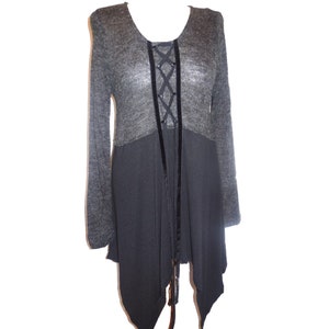 May include: A gray and black tunic-style top with long sleeves. The top features a lace-up detail on the front with black ribbon and a layered design. The upper portion is a lighter gray, while the lower section is a darker gray.