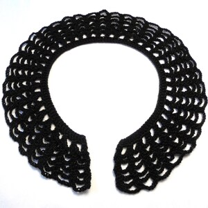 May include: A black crocheted collar with a scalloped edge. The collar is open in the front and is designed to be worn around the neck. The intricate openwork design adds a delicate touch to the accessory.