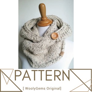 May include: A cream-colored knitted cowl with a wooden button closure. The cowl is made with a chunky yarn and has a textured stitch pattern. The cowl is displayed on a wooden mannequin.