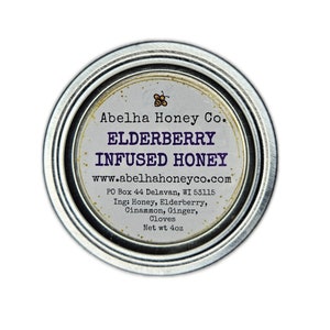 May include: A silver lidded jar with a white label that reads "Abelha Honey Co. ELDERBERRY INFUSED HONEY www.abelhahoneyco.com PO Box 44 Delavan, WI 53115 Ing: Honey, Elderberry, Cinammon, Ginger, Cloves Net wt 4oz"