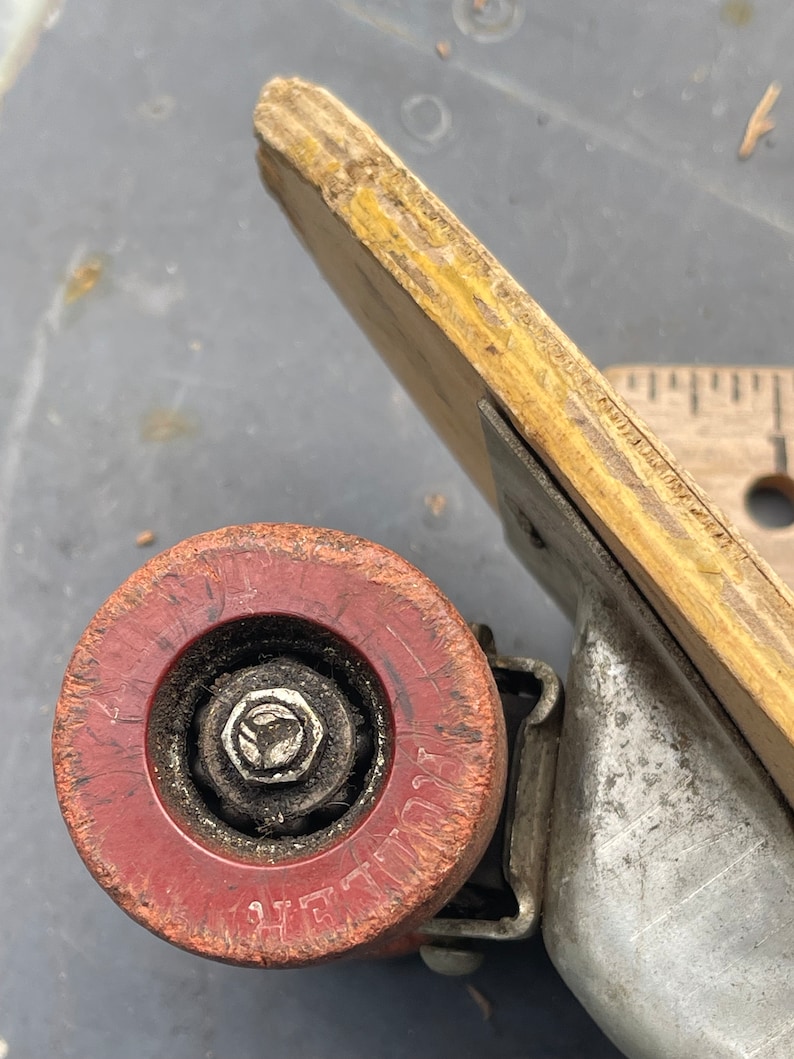 K&ouml;nnte beinhalten: Nahaufnahme eines roten Skateboard-Rads mit einer Metallachse und einer abgenutzten Oberfl&auml;che. Das Rad tr&auml;gt den Schriftzug "ZEPHYR".