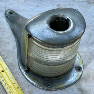 May include: A chrome-plated boat navigation light with a clear lens and a ribbed design. The light has a mounting bracket and two holes for attaching it to a surface.