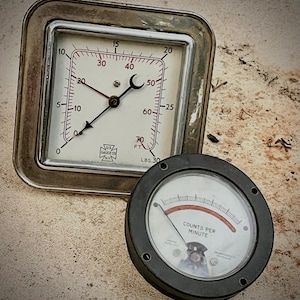 May include: Two vintage gauges. One is square with a white face, black and red markings, and a needle pointing to 20. The other is round with a black frame and a needle pointing to the right. The square gauge reads "LBS 30".