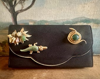 Vintage 1960s Harrods London black fabric clutch adorned with vintage alligator, snake, jade stone gold-tone brooches, one-of-a-kind