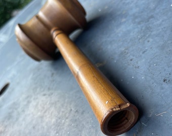 May include: A wooden gavel with a brown finish. The gavel has a round head and a long, cylindrical handle.