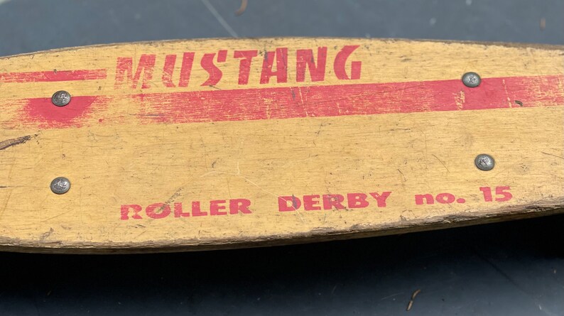 K&ouml;nnte beinhalten: Vintage Holz-Roller-Derby-Brett mit roter und wei&szlig;er Farbe und den aufgedruckten Worten "Mustang Roller Derby No. 15".