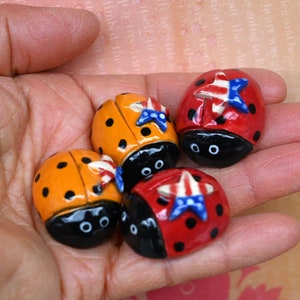 May include: Four ladybug figurines with red, black, yellow, and blue paint. Each ladybug has a star-shaped design on its back with red, white, and blue colors.