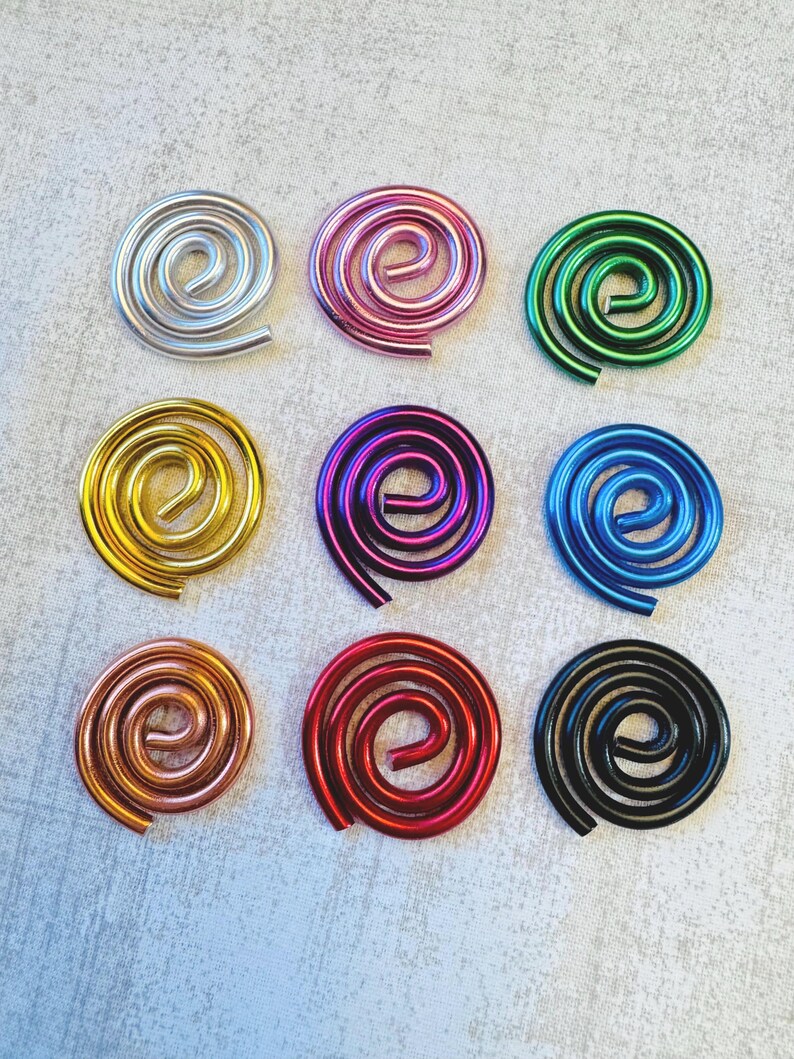 May include: Nine colorful metal spiral ornaments in silver, pink, green, gold, purple, blue, copper, red, and black. Each spiral is a unique, eye-catching design, perfect for crafts or decorative purposes.