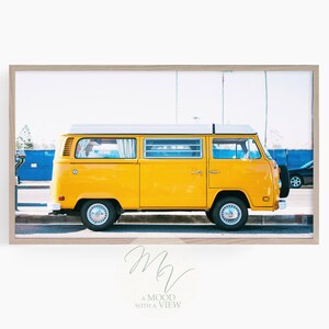 Könnte beinhalten: Ein gelber Vintage-Van, der auf einer Straße mit einem blauen Gebäude im Hintergrund geparkt ist.