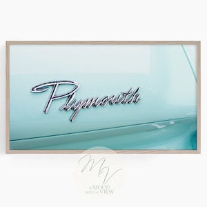 Könnte beinhalten: Nahaufnahme des Hecks eines Oldtimers mit einem verchromten "Plymouth"-Emblem auf hellblauem Hintergrund.