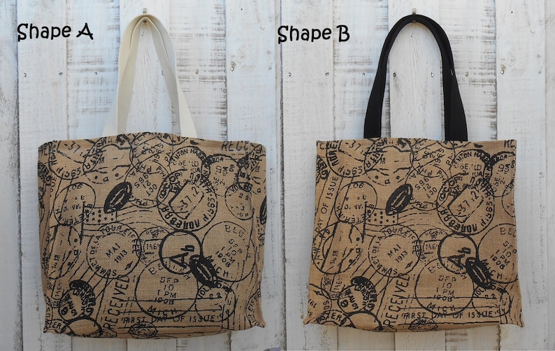 May include: Two tote bags with a brown canvas fabric and black printed postage stamps. The bag on the left has white handles and the bag on the right has black handles.