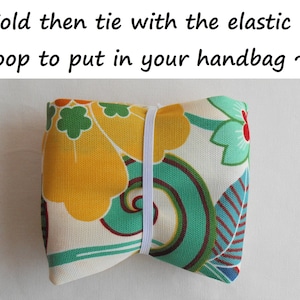 May include: A folded fabric pouch with a floral pattern in shades of yellow, green, and red. The pouch is tied with a white elastic band. "Fold then tie with the elastic loop to put in your handbag ~" is written above the image.