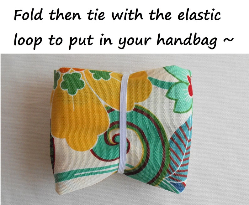 May include: A folded fabric pouch with a floral pattern in shades of yellow, green, and red. The pouch is tied with a white elastic band. "Fold then tie with the elastic loop to put in your handbag ~" is written above the image.