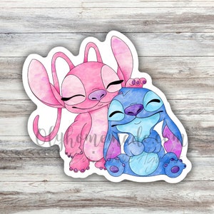 May include: A watercolour illustration of two cartoon characters, Stitch and Angel, hugging. Stitch is blue with a purple nose and Angel is pink with a purple nose. Both characters have closed eyes and are smiling.