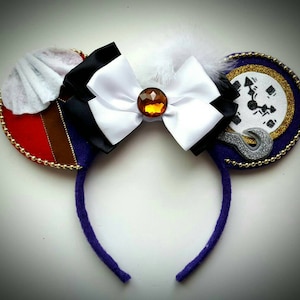 May include: Purple headband with a white bow and a red, brown, and black ear with a white feather and a purple ear with a gold and silver clock face.