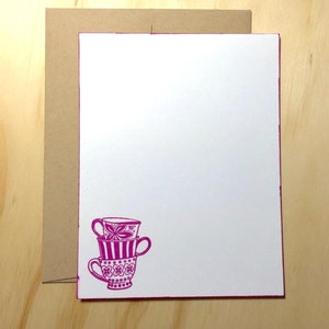 May include: A stack of three pink teacups with floral and striped patterns on a white background.