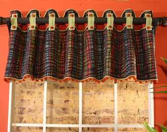 May include: A window valance with a geometric pattern in shades of red, orange, blue, and green. The valance has a scalloped edge and a fringe trim. It is hung on a brown curtain rod with decorative finials.