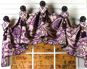 May include: A purple and cream patterned valance with a scalloped edge and tassels. The valance is hung on black metal hooks.