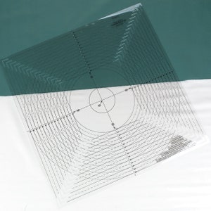 May include: A clear plastic circle template with concentric circles and lines for quilting and sewing projects. The template is marked with measurements in inches.