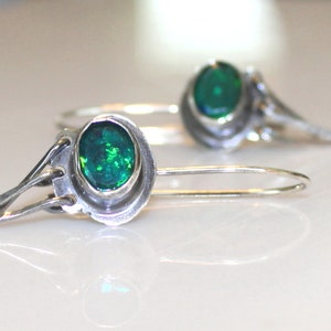 May include: A pair of silver earrings with green gemstone accents. The earrings have a delicate, intricate design.