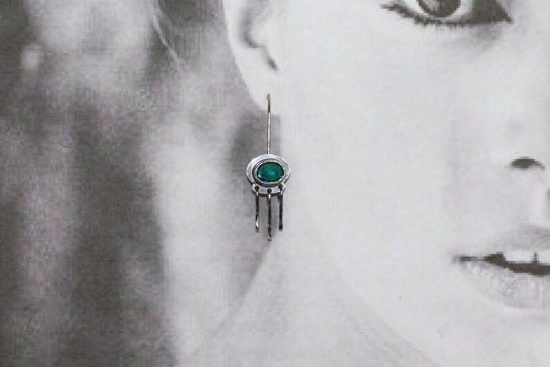 May include: Silver dangle earrings with a green gemstone and a delicate chain design.