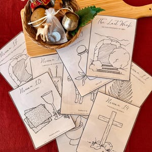 May include: A woven basket filled with miniature religious figures, a loaf of bread, and small bottles, sits on a wooden cutting board. Several cards with black and white illustrations and text are fanned out around the basket. The cards have titles like "Nissan 13" and "The Last Week".