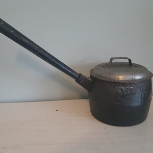 May include: A black cast iron pot with a long wooden handle and a silver lid. The pot has the text "Mrs. Swain" embossed on the side.