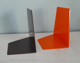 May include: Two bookends, one black and one orange, made of a smooth, glossy material. The bookends are angled to hold books upright.