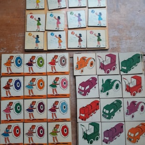 Puede incluir: Un juego de cartas educativas vintage de madera. Las cartas presentan ilustraciones coloridas de niños jugando con pelotas y paraguas, y varios vehículos, incluyendo un tractor, un cochecito, un tren, un camión y un coche.