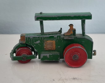 May include: A green toy steamroller with a red roller and a yellow driver in the cab. The toy is made of metal and has a worn paint finish.