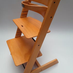 Puede incluir: Silla alta de madera con acabado natural. Cuenta con respaldo curvo, dos niveles de asiento ajustables y reposapi&eacute;s. El dise&ntilde;o es sencillo y funcional, centrado en la seguridad y comodidad del ni&ntilde;o. Fabricada en madera maciza.