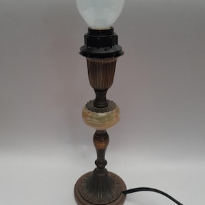 May include: An antique table lamp with a white globe bulb. The lamp features a bronze-colored base and stem, with a decorative green and cream-colored stone accent. The lamp has a black power cord.