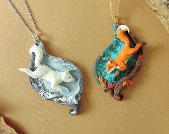 May include: Two fox pendants on chains. One fox is white and leaping through a snowy forest scene. The other fox is orange and leaping through a forest scene with fall leaves.