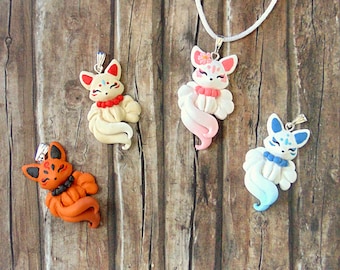 May include: Four fox charm necklaces with different colored tails. The charms are made of polymer clay and feature white faces with black eyes and pink noses. The tails are white, pink, blue, and orange.