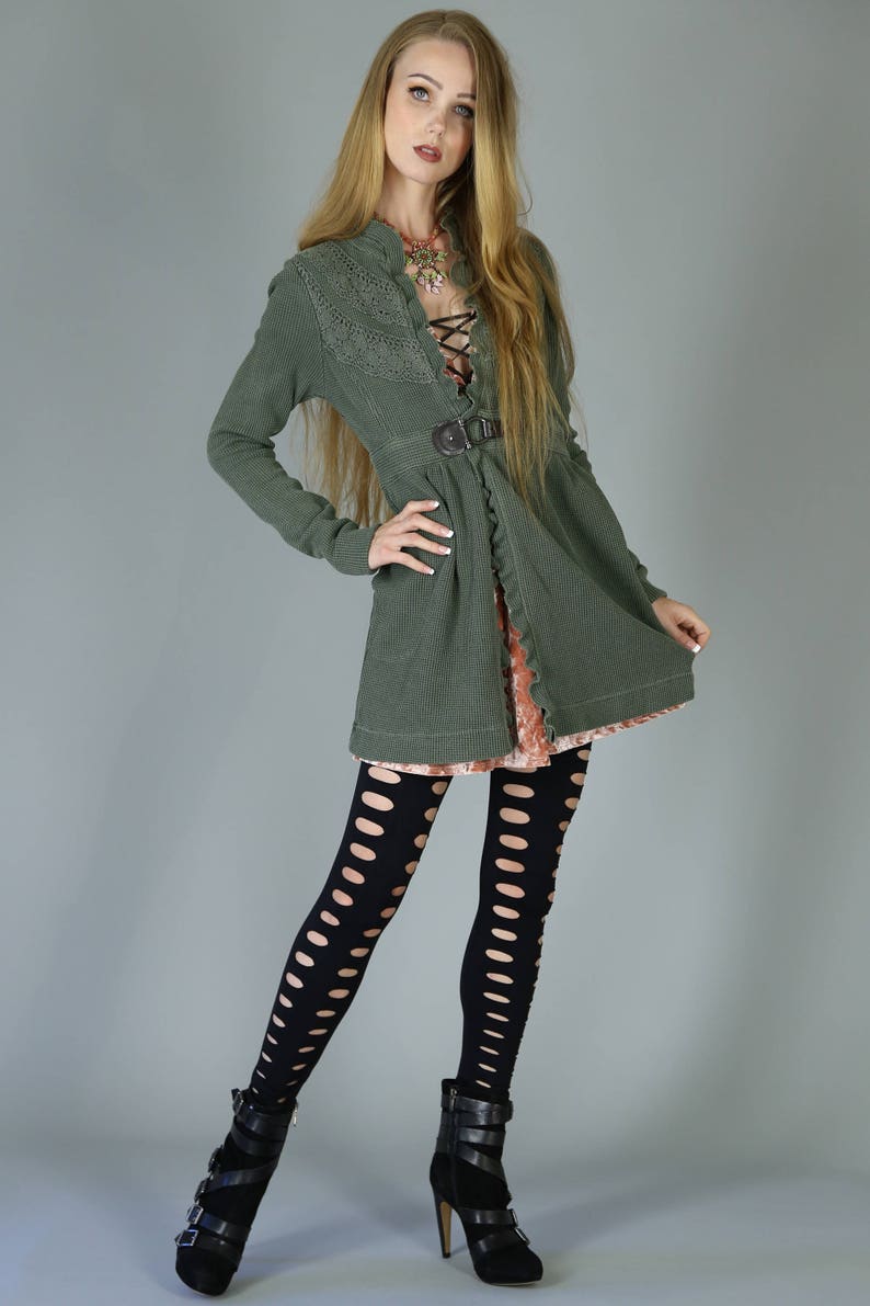May include: A woman wearing a green, lace-trimmed cardigan with a brown belt, black fishnet tights, and black ankle boots.