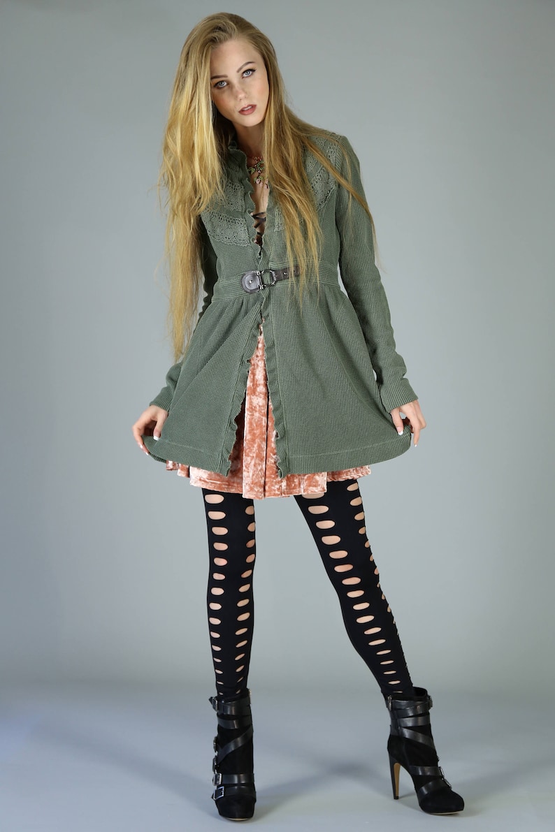 May include: A woman wearing a green corduroy jacket with a lace overlay, a pink velvet skirt, black fishnet tights, and black heeled boots.