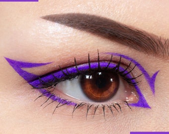 May include: Close-up of a woman's eye with bold purple eyeliner creating a dramatic winged shape. The eyeliner is applied along the lash line and extends outwards in a sharp angle.