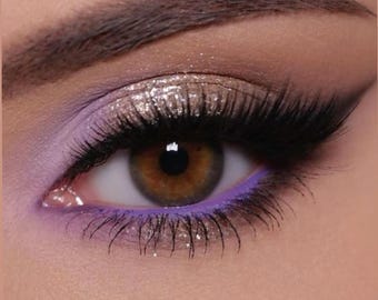 May include: Close-up of an eye with purple and silver eyeshadow, black eyeliner, and long eyelashes.