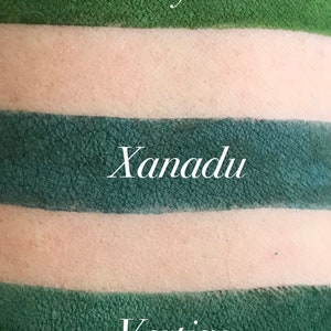 Puede incluir: Primer plano de tres muestras de sombra de ojos verdes sobre la piel. La muestra superior est&aacute; etiquetada como "Ivy", la del medio "Xanadu" y la inferior "Vertigo". Las muestras son de varios tonos de verde, con un tono de piel claro en el medio.