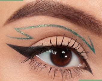 May include: Close-up of an eye with black eyeliner and a green glitter eyeliner in the shape of a lightning bolt.