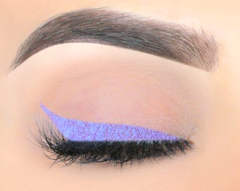 May include: Close-up of an eye with a purple glitter eyeliner and black eyelashes.
