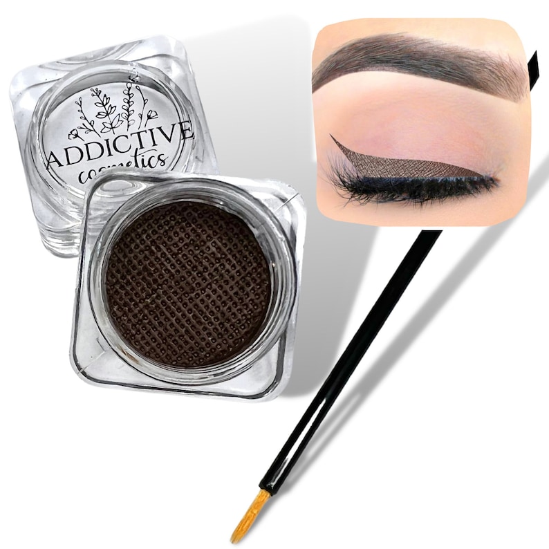 Pode incluir: Um pote de delineador de olhos em gel marrom com um pequeno aplicador de pincel. O pote &eacute; transparente e tem o texto "ADDICTIVE cosmetics" na tampa. O delineador &eacute; mostrado aplicado em um olho, criando um look de delineador de olhos alado.