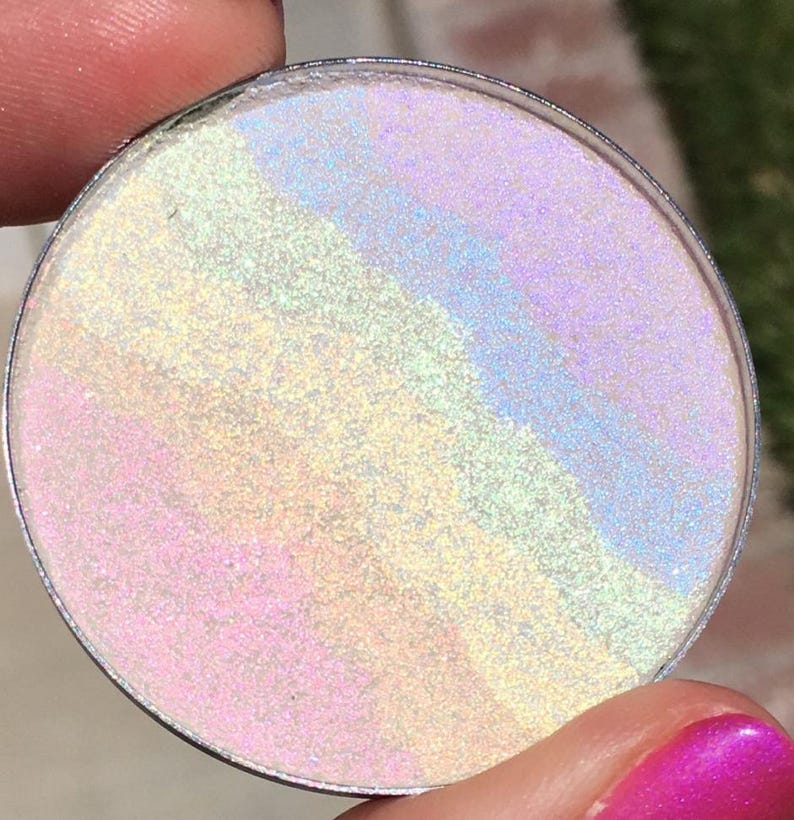 May include: A round, iridescent, white, and light blue glitter pigment in a clear container.