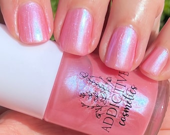 May include: Pink nail polish with a pearlescent finish. The bottle is labeled "ADDICTIVE cosmetics".